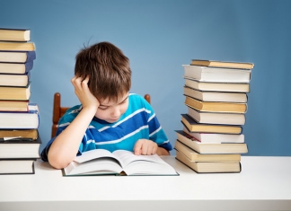 Bub mit Bücherstapel lesend