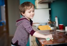 Kind putzt die Arbeitsfläche in der Küche