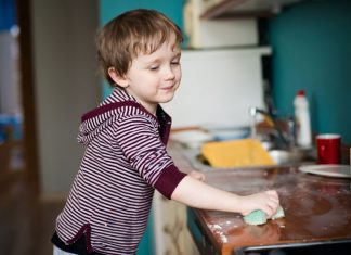 Kind putzt die Arbeitsfläche in der Küche