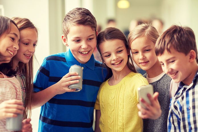 Schulkinder schauen auf ein Handy