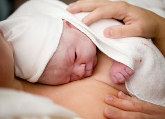 Neugeborenes liegt am Bauch der Mutter