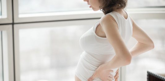 Schwangere hält sich den Rücken