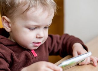 Kind spielt mit Handy Kinderfotos im Netz