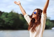 Frau streckt Arme der Sonne entgegen