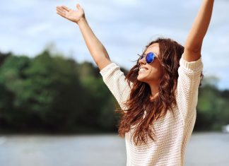 Frau streckt Arme der Sonne entgegen