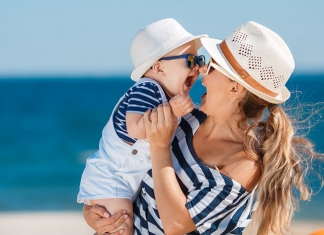 Mutter mit lachendem Baby am Strand