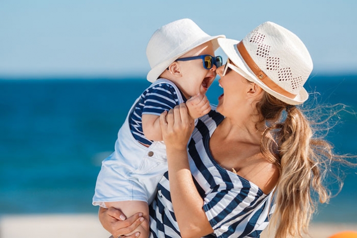 Mutter mit lachendem Baby am Strand