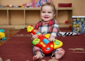 lachendes Baby mit Spielzeug-Gitarre