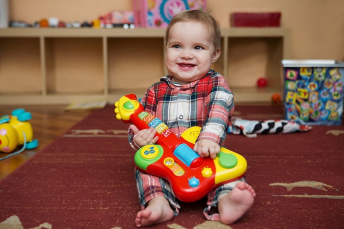 lachendes Baby mit Spielzeug-Gitarre