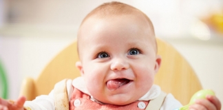 Baby im Hochstuhl mit Löffel