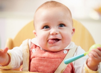 Baby im Hochstuhl mit Löffel