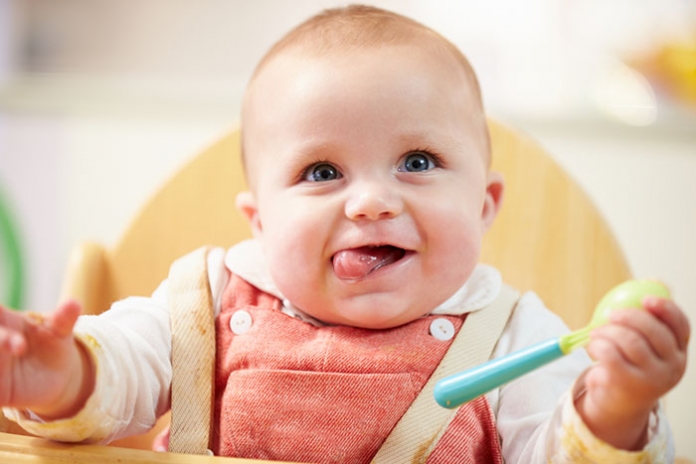 Baby im Hochstuhl mit Löffel