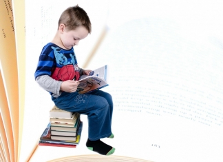 Kind sitz auf einem Stapel Bücher