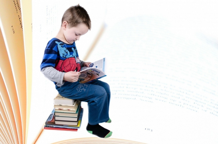 Kind sitz auf einem Stapel Bücher